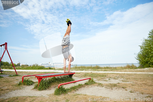 Image of young man exercising on bench outdoors