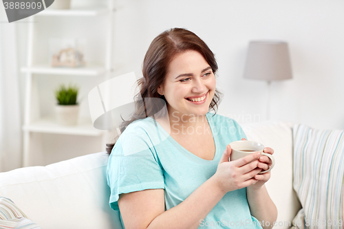 Image of happy plus size woman with cup of tea at home