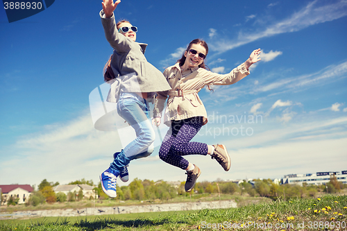 Image of happy little girls jumping high outdoors