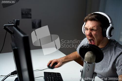 Image of man in headset playing computer video game at home