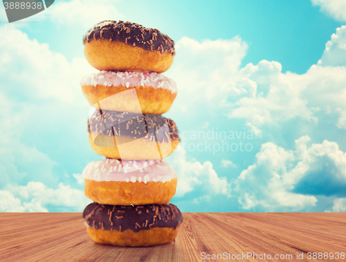 Image of close up of glazed donuts pile over blue sky