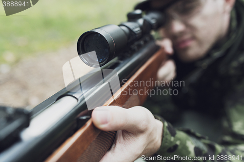 Image of close up of soldier or hunter with gun in forest