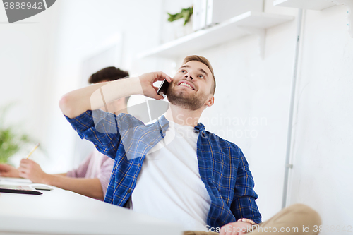 Image of happy creative man calling on cellphone at office