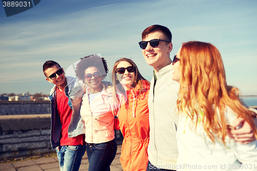 Image of happy teenage friends walking along city street