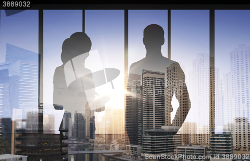 Image of silhouettes of business partners over city office