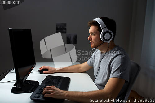 Image of man in headset playing computer video game at home