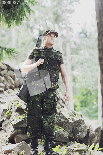 Image of young soldier or hunter with gun in forest