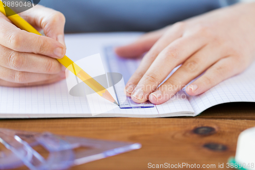 Image of close up of hands with ruler and pencil drawing 