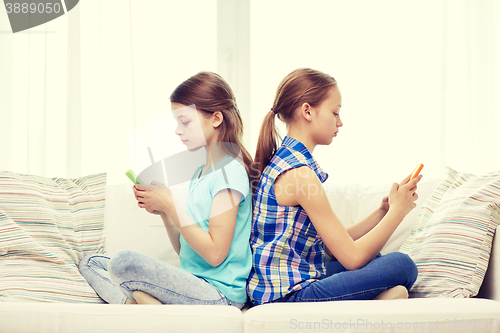 Image of girls with smartphones sitting on sofa at home