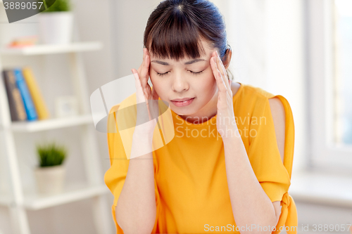 Image of tired asian woman suffering from headache at home