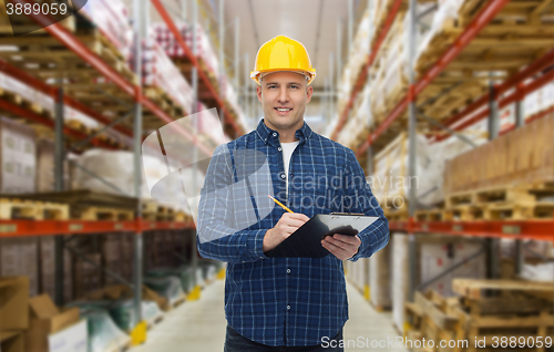 Image of happy man in helmet with clipboard at warehouse