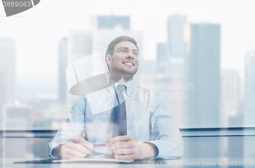 Image of smiling businessman sitting in office