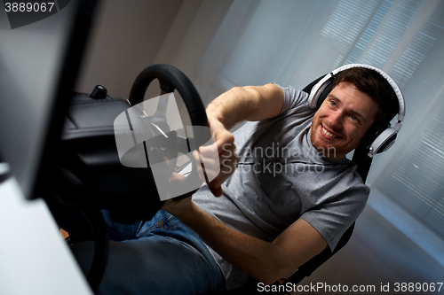 Image of man playing car racing video game at home