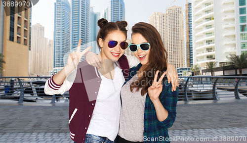 Image of smiling teenage girls in sunglasses showing peace