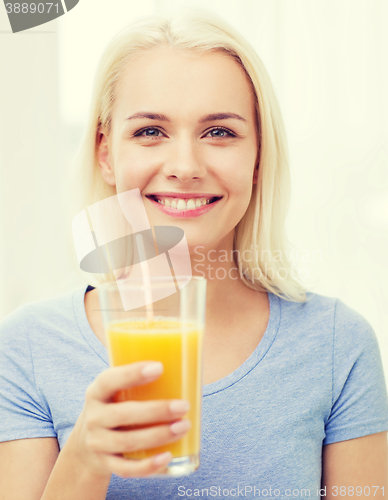 Image of smiling woman drinking orange juice at home