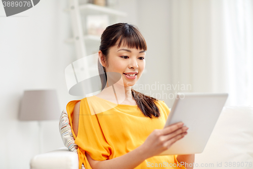 Image of happy young asian woman with tablet pc at home