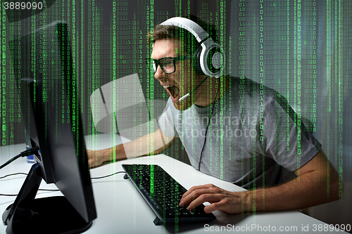 Image of man in headset playing computer video game at home