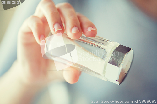 Image of close up of hand holding white salt cellar