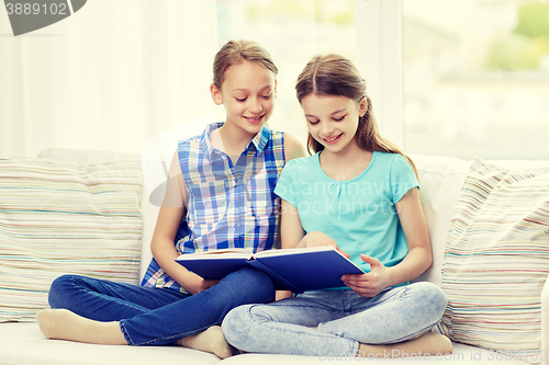 Image of two happy girls reading book at home