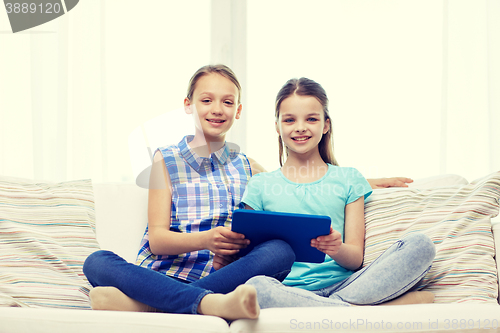 Image of happy girls with tablet pc sitting on sofa at home