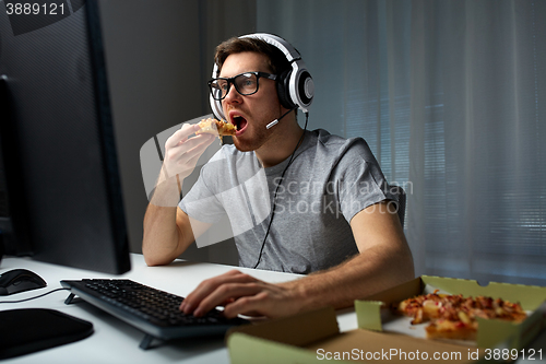 Image of man in headset playing computer video game at home