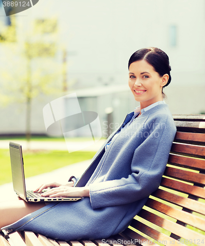 Image of smiling business woman with laptop in city