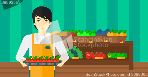 Image of Supermarket worker with box full of apples.