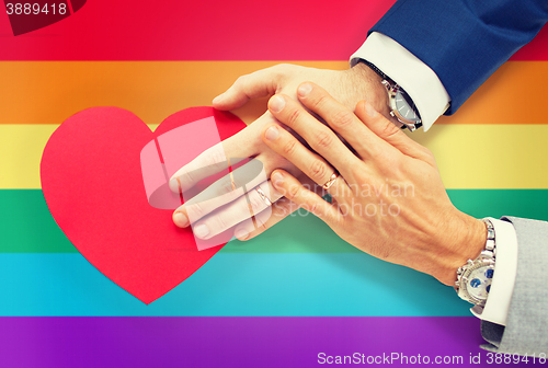 Image of close up of male gay couple hands with red heart