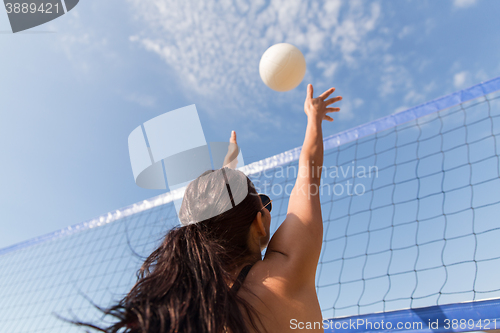 Image of young woman with ball playing volleyball on beach