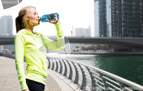 Image of woman drinking water after doing sports outdoors