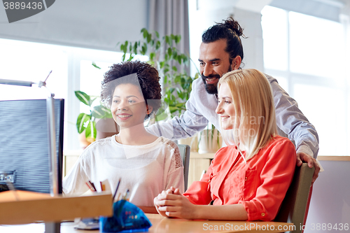 Image of happy creative team with computer in office