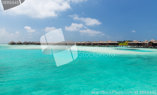 Image of bungalow huts in sea water on exotic resort beach