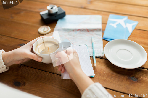 Image of close up of hands with coffee cup and travel stuff