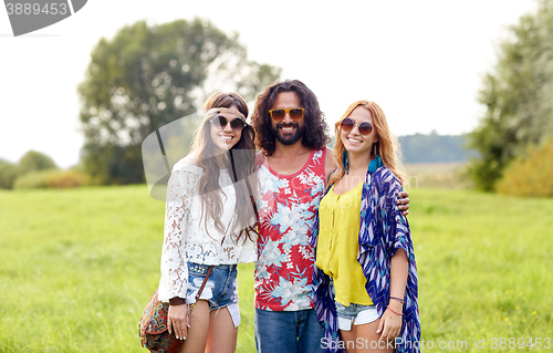 Image of smiling young hippie friends on green field