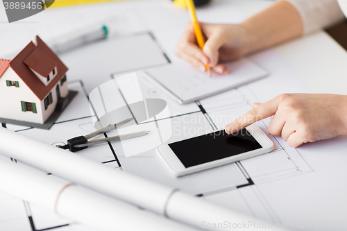 Image of close up of hands with blueprint and smarphone