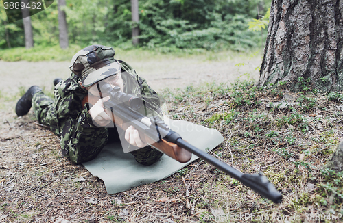 Image of young soldier or hunter with gun in forest