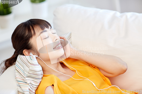 Image of happy asian woman with earphones listening music