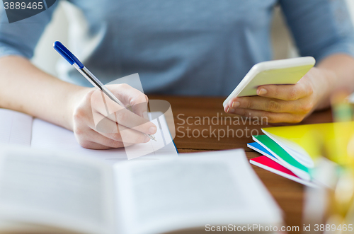 Image of close up of student with smartphone and notebook