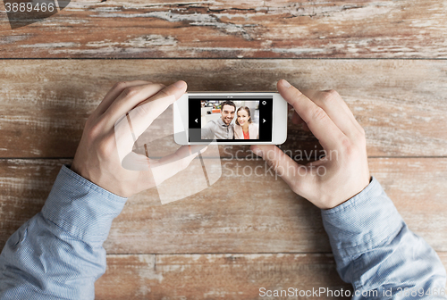 Image of close up of male hands with photo on smartphone