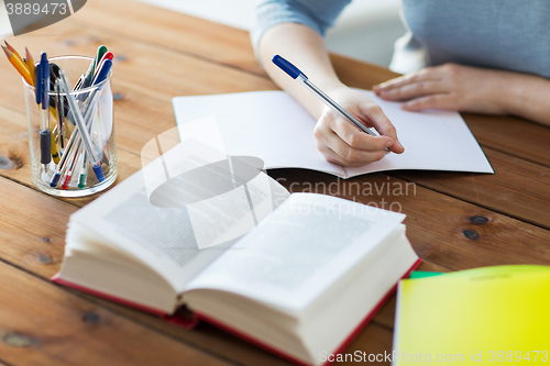 Image of close up of student with book and notebook at home
