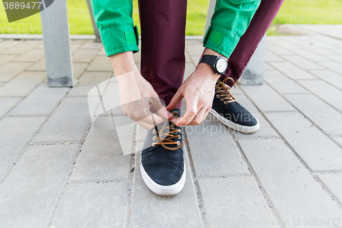 Image of close up of male hands tying shoe laces on street