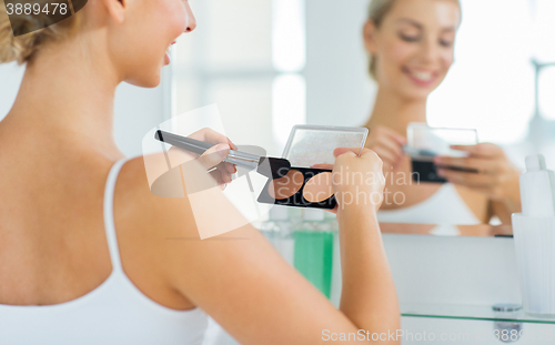 Image of woman with makeup brush and foundation at bathroom