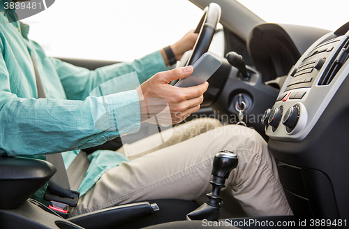 Image of close up of man with smartphone driving car