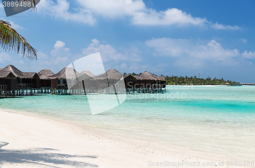 Image of bungalow huts in sea water on exotic resort beach