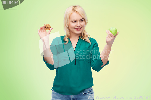 Image of smiling woman choosing between apple and cookie