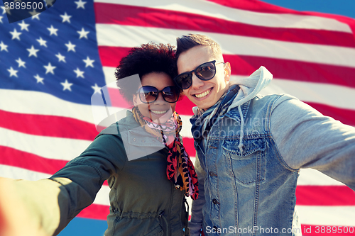 Image of happy couple taking selfie over american flag