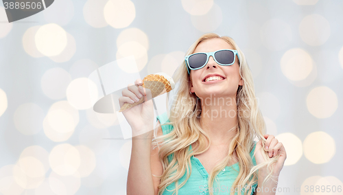 Image of happy young woman in sunglasses eating ice cream