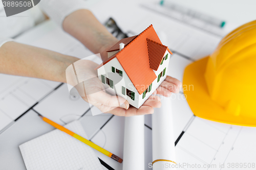 Image of close up of hands with house model above blueprint