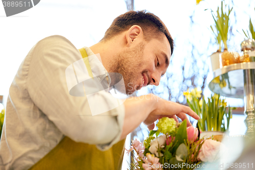 Image of smiling florist man making bunch at flower shop