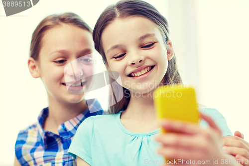 Image of happy girls with smartphone taking selfie at home